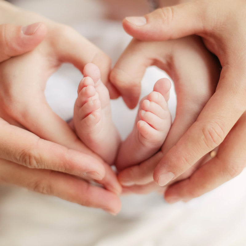 Heart hands around a newborn baby's feet