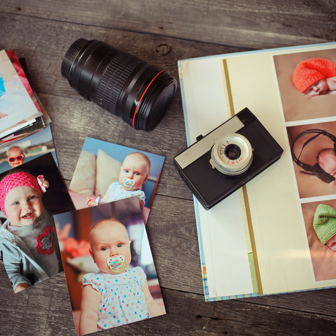 Baby photos, album and retro camera on a wooden table