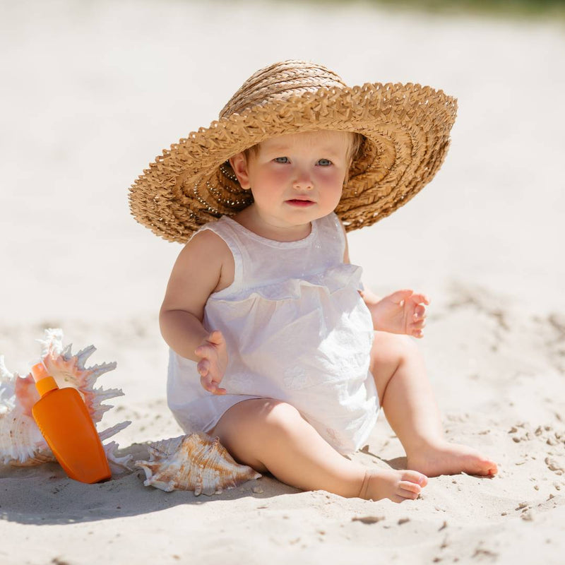 Baby on the beach wearing a wide-brimmed hat