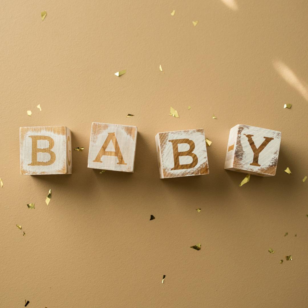 The word "baby" written out in baby blocks, surrounded by gold glitter
