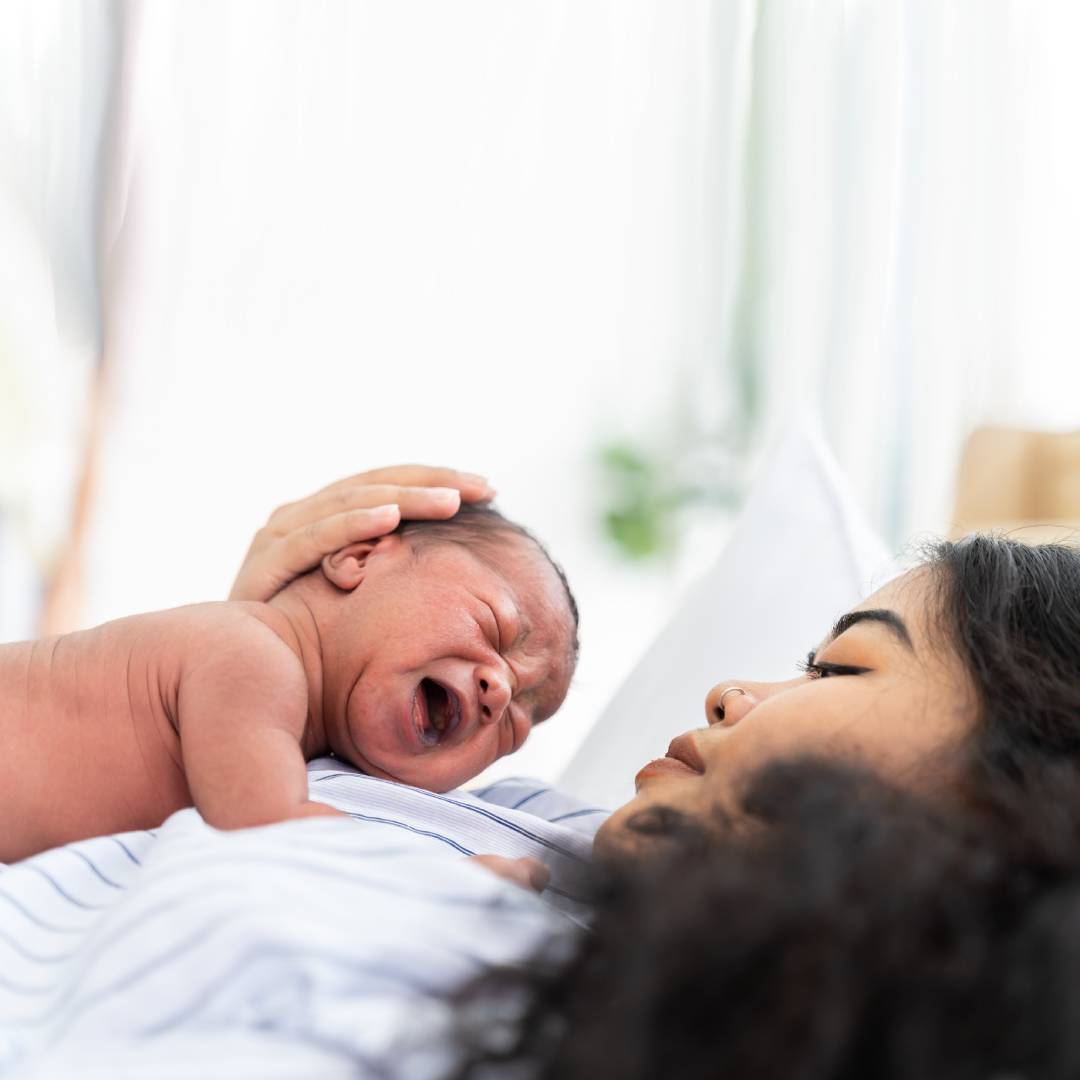 Crying baby lying on mum's chest