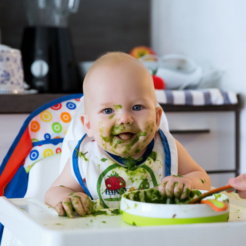 Happy baby covered in green food