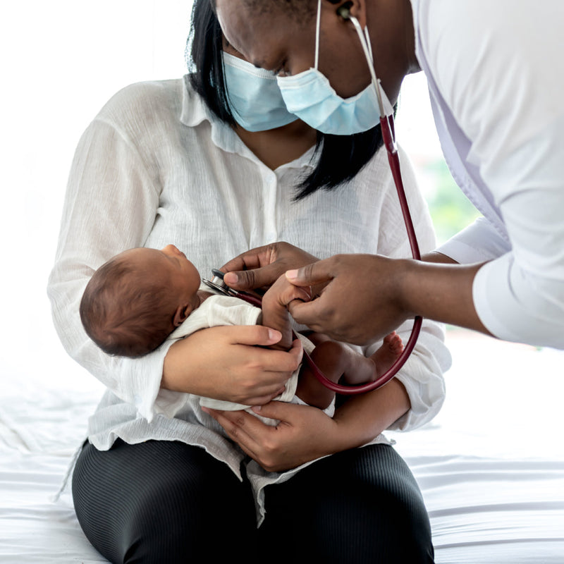 A doctor checks a newborn baby with a stethoscope