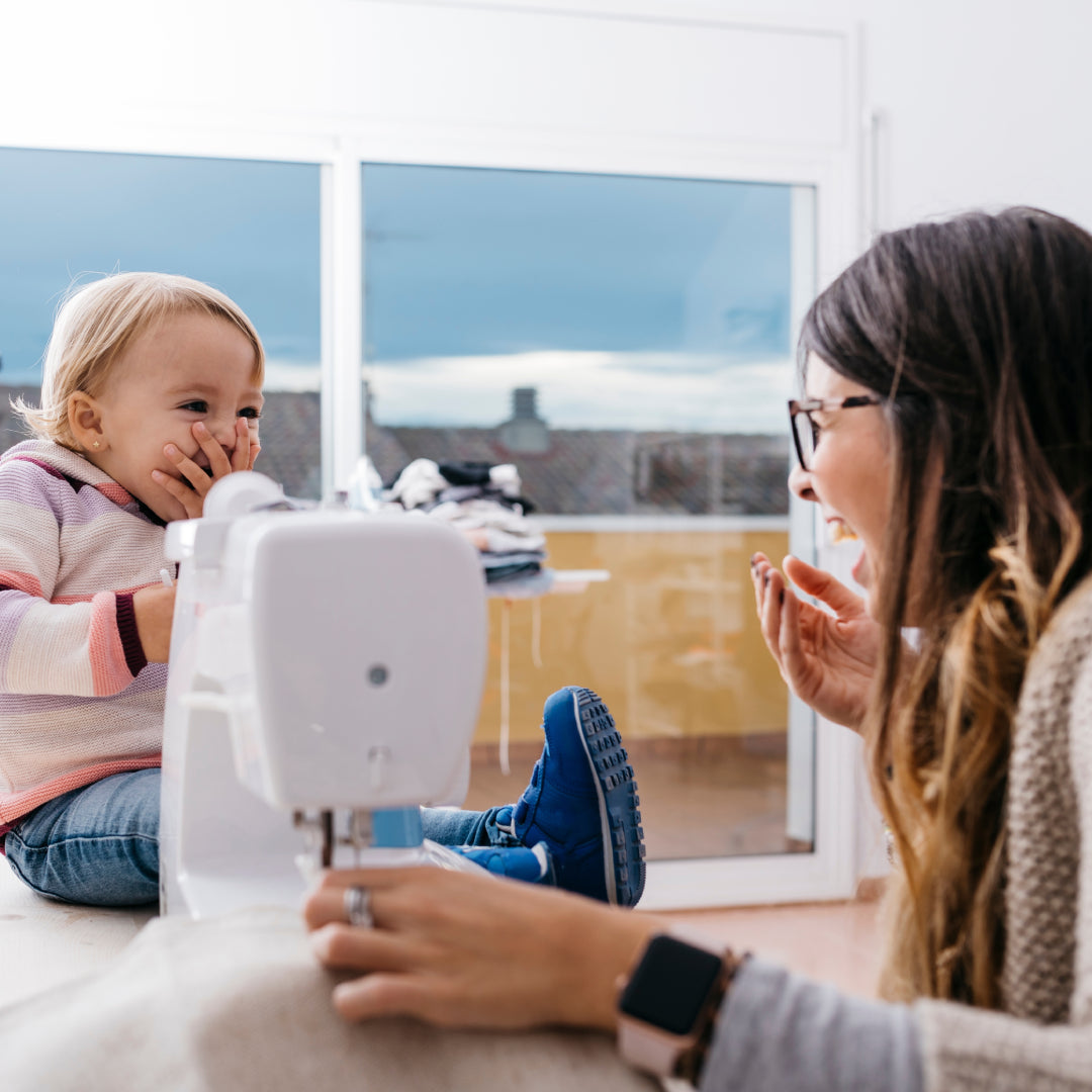 Mother and toddler sewing and laughing