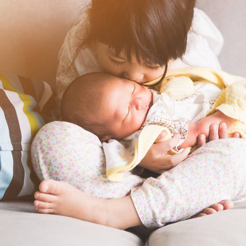 Toddler kissing their younger sibling after meeting for the first time